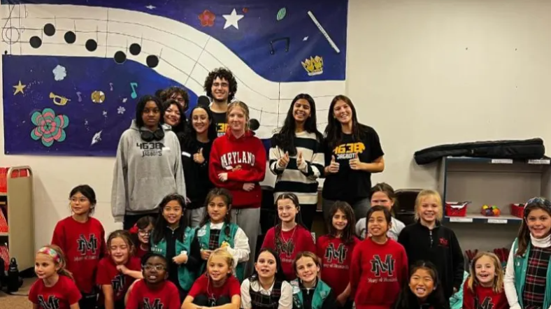 A group of young people posing together, including participants in robotics team shirts.