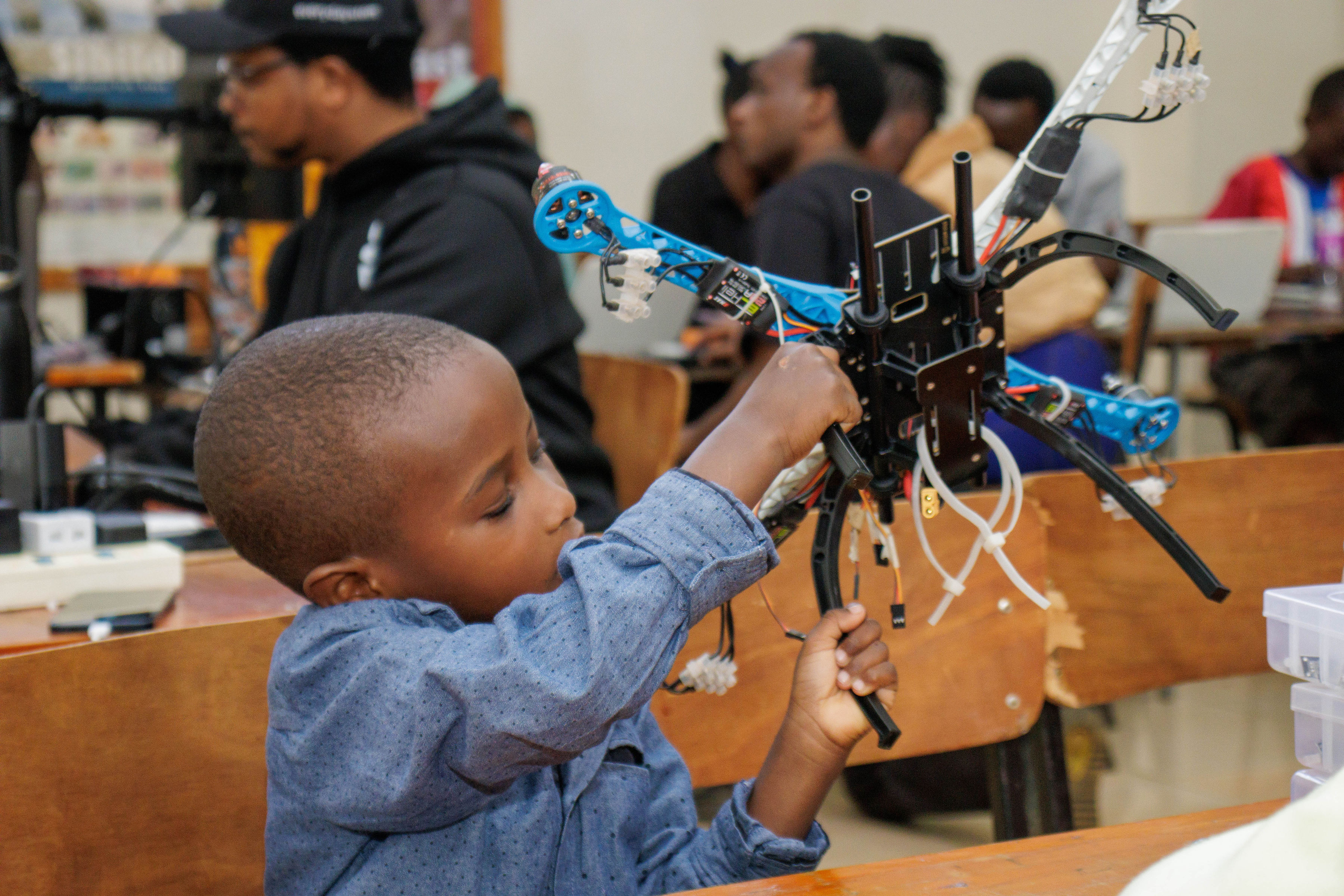 A young participant exploring a drone frame at a Kenya chapter activity.